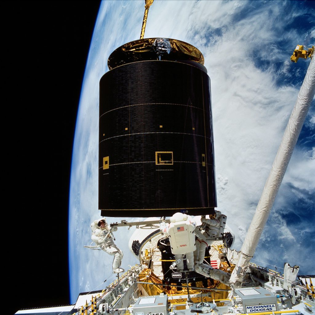 During the world's first (and so far only) 3-person EVA, space shuttle astronauts salvage a stranded communications satellite. (1992 May 13, NASA.)