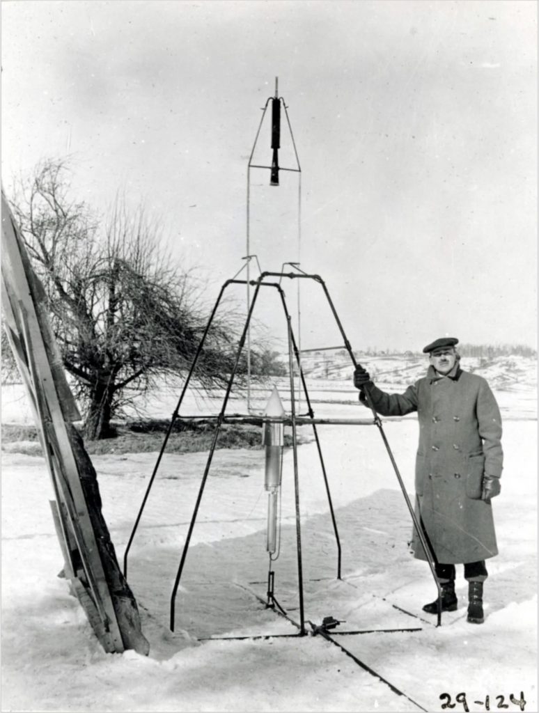 Goddard standing next to the first liquid-fueled rocket
